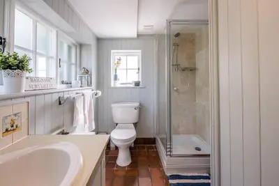 a bathroom with a toilet and a shower and a sink at Margo's Cottage, Orford in Orford