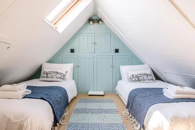 two beds in a attic room with a blue door at Margo's Cottage, Orford in Orford