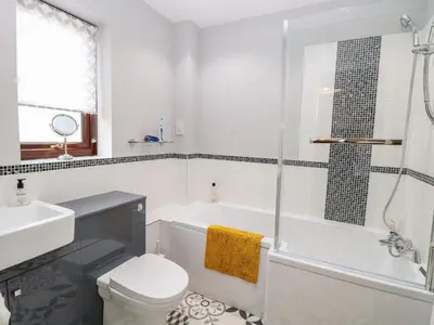 a bathroom with a tub and a toilet and a sink at Village Retreat in Ely