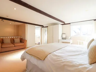 a bedroom with a large white bed and a couch at Vine Cottage in Halstead
