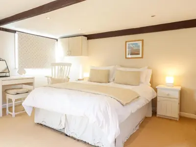 a bedroom with a large white bed and a window at Vine Cottage in Halstead