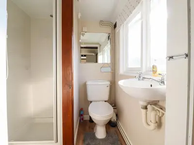 a bathroom with a toilet and a sink and a window at Vine Cottage in Halstead