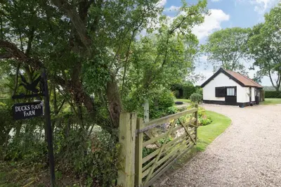 a sign in front of a house with a fence at Garden Cottage in Diss