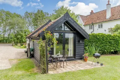 an extension to a house with a garden and a patio at Garden Cottage in Diss