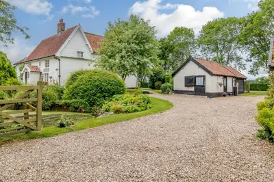 a house with a garden and a driveway at Garden Cottage in Diss