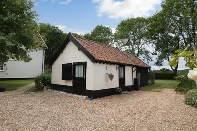 a small white house with a brown roof at Garden Cottage in Diss