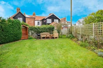 a backyard with a wooden fence and a table and chairs at 4 Old Homes, Thorpeness - Only a stones throw from the beach - Aldeburgh Coastal Cottages in Thorpeness