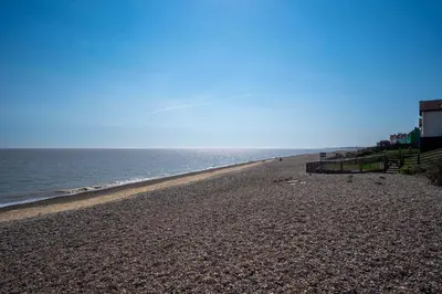 a beach with the ocean on a sunny day at 4 Old Homes, Thorpeness - Only a stones throw from the beach - Aldeburgh Coastal Cottages in Thorpeness