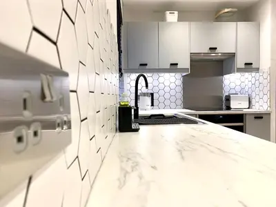 a kitchen with white cabinets and a marble counter top at Stylish Cambridge Pad in Bar Hill