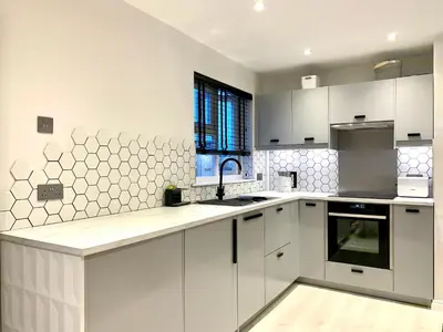 a white kitchen with white cabinets and a sink at Stylish Cambridge Pad in Bar Hill