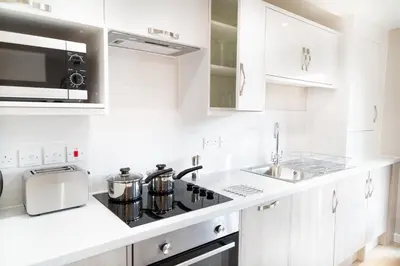 a white kitchen with a stove and a sink at Citystay Living - Hinton House in Cambridge