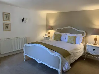 a bedroom with a large white bed with two tables at Kings Head Low House in Laxfield