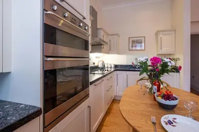 a kitchen with a wooden table and a large oven at Polly's - Aldeburgh Coastal Cottages in Aldeburgh