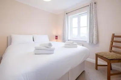 a bedroom with a large white bed with towels on it at Pinky Cottage in Aldeburgh
