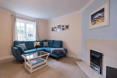 a living room with a blue couch and a fireplace at Pinky Cottage in Aldeburgh