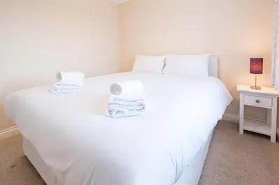 a bedroom with a white bed with towels on it at Pinky Cottage in Aldeburgh