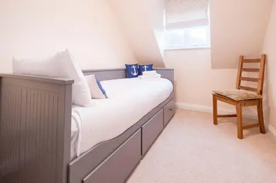 a bedroom with a large bed with a wooden chair at Pinky Cottage in Aldeburgh