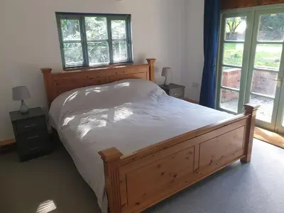 a bedroom with a large wooden bed and windows at Church Farm Lodge in Southburgh
