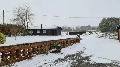 a brick wall covered in snow with a house in the background at Church Farm Lodge in Southburgh