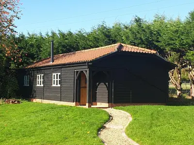 a black shed with an open door on a grass field at Church Farm Lodge in Southburgh