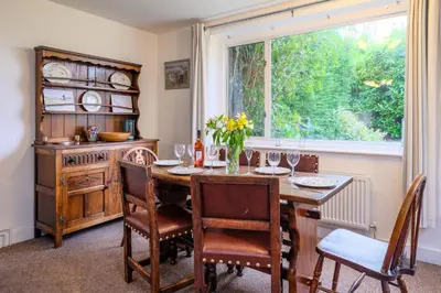 a dining room with a wooden table and a window at Beaver Cottage in Aldeburgh