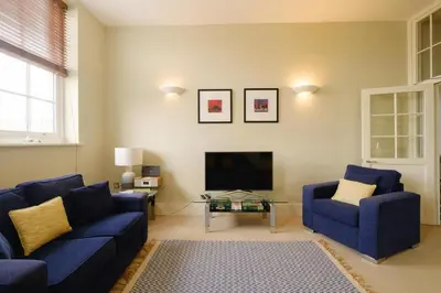 a living room with two blue couches and a fireplace at Beachcomber - Aldeburgh Coastal Cottages in Aldeburgh