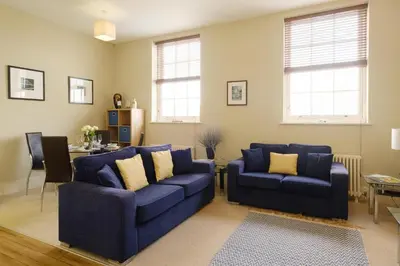 a living room with two blue couches and a table at Beachcomber - Aldeburgh Coastal Cottages in Aldeburgh