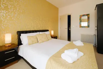 a bedroom with a large white bed and two lamps at Beachcomber - Aldeburgh Coastal Cottages in Aldeburgh