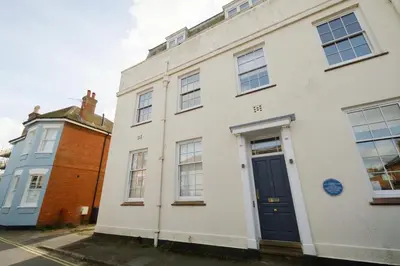 a white house with a blue door on a street at Beachcomber - Aldeburgh Coastal Cottages in Aldeburgh