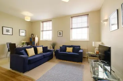 a living room with two blue couches and a tv at Beachcomber - Aldeburgh Coastal Cottages in Aldeburgh