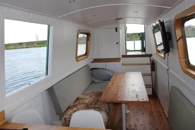 a table in the back of a boat with two windows at Waterbeach Boatel in Cambridge