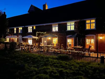 a building with tables and chairs and umbrellas at night at The Bell Inn in Thorpe le Soken