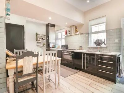 a kitchen with a wooden table and a dining room at Saxon Lodge Cottage in Felixstowe