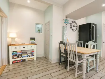 a kitchen with a table and chairs and a refrigerator at Saxon Lodge Cottage in Felixstowe
