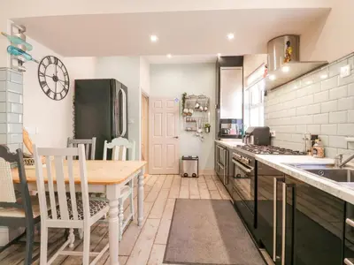 a kitchen with a wooden table and a counter top at Saxon Lodge Cottage in Felixstowe