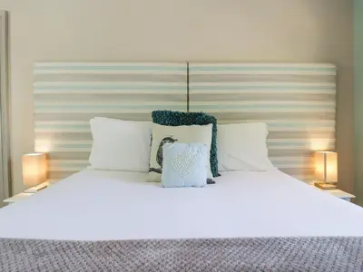 a large bed with white sheets and pillows at Saxon Lodge Cottage in Felixstowe
