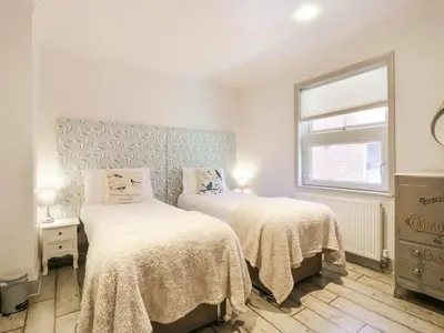 a bedroom with two beds and a window at Saxon Lodge Cottage in Felixstowe