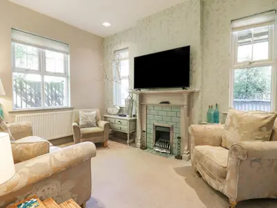 a living room with a fireplace and a flat screen tv at Saxon Lodge Cottage in Felixstowe