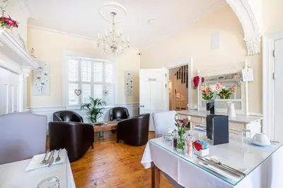 a living room with a table and chairs and a chandelier at Hamiltons Boutique Hotel in Southend-on-Sea