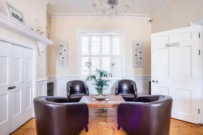 a living room with leather chairs and a wooden table at Hamiltons Boutique Hotel in Southend-on-Sea
