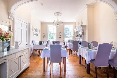 a dining room with white tables and purple chairs at Hamiltons Boutique Hotel in Southend-on-Sea