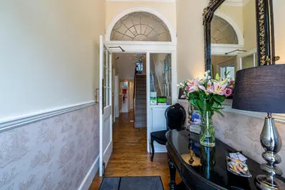 a hallway with a mirror and a vase of flowers on a table at Hamiltons Boutique Hotel in Southend-on-Sea