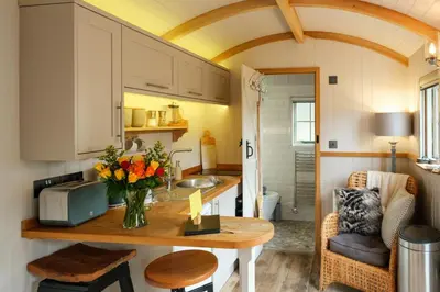 a kitchen with a table with a vase of flowers at Piano Forte - a delightful rural shepherd hut & hot tub available ! in Rushford