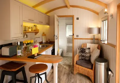 a kitchen with a table in a tiny house at Piano Forte - a delightful rural shepherd hut & hot tub available ! in Rushford