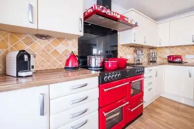 a red stove top oven in a kitchen with white cabinets at 69 Saxmundham Road in Aldeburgh