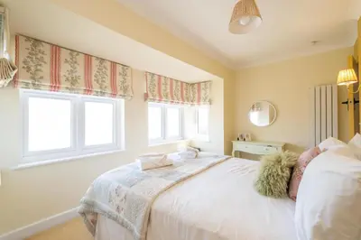 a bedroom with a bed and two windows at 69 Saxmundham Road in Aldeburgh