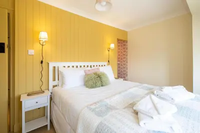 a bedroom with a white bed and a yellow wall at 69 Saxmundham Road in Aldeburgh