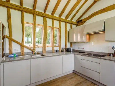a kitchen with white cabinets and a wooden ceiling at Blackwell Barn in Raydon