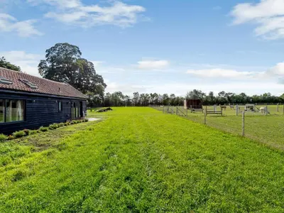 a large grass field next to a building at Blackwell Barn in Raydon
