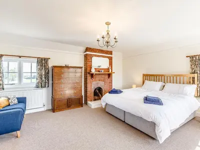 a bedroom with a large bed and a fireplace at Mark Farmhouse in Bradwell on Sea